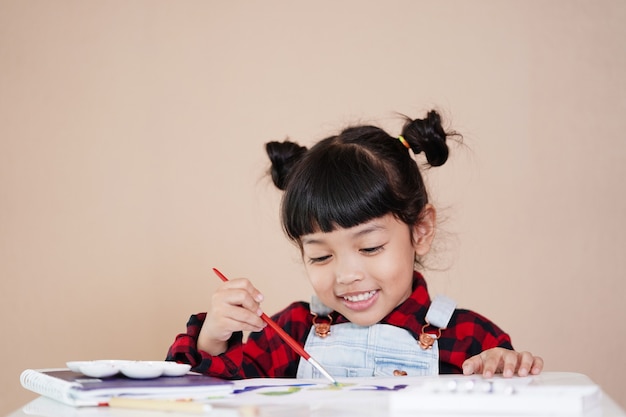 Gelukkig Aziatisch kind dat thuis leert en geniet van Aquarel Tekenen.