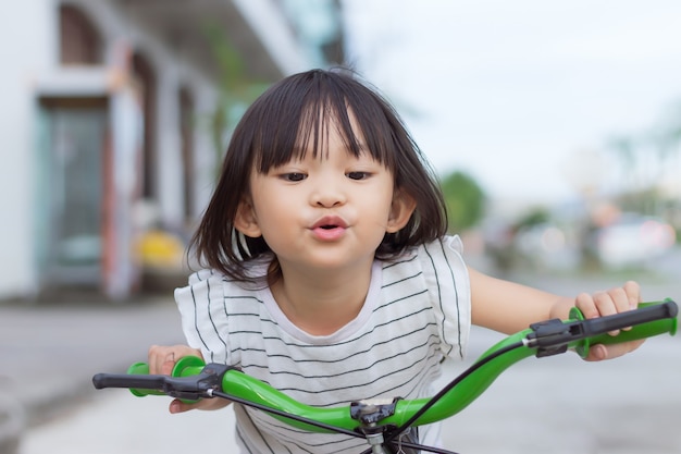 Gelukkig aziatisch kindmeisje fietst in het park buiten oefening voor gezondheid en sport