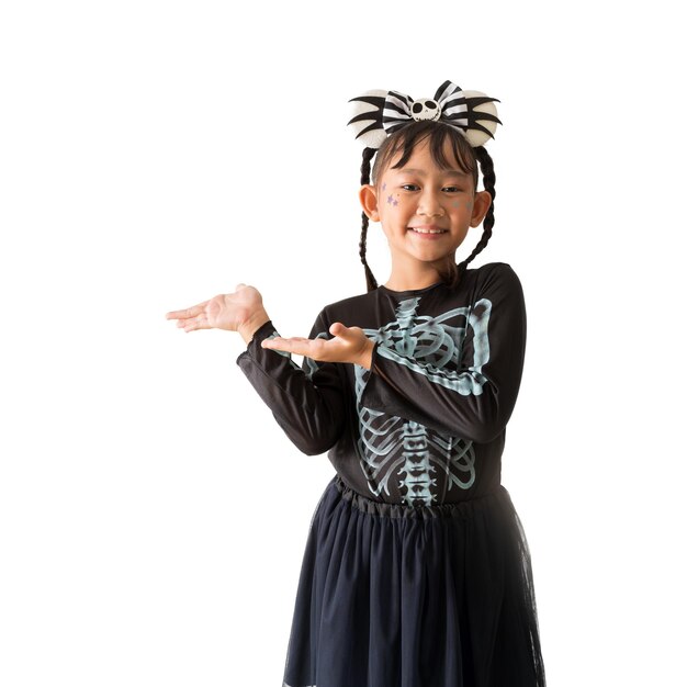 Gelukkig Aziatisch klein meisje draagt Halloween-kostuum en staande handen wijzende presentatie naar de zijkant geïsoleerd op witte en transparante achtergrond Uitknippaden voor ontwerpwerk