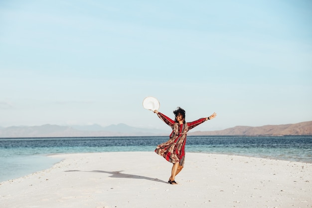 Gelukkig Aziatisch meisje dansen op wit zandstrand omringd door de zee