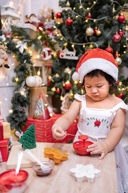 Gelukkig Aziatisch meisje dat peperkoek thuis kookt met ouder voor eerste kerstdag. Zelfgemaakte kerstkoekjes voor kinderen.