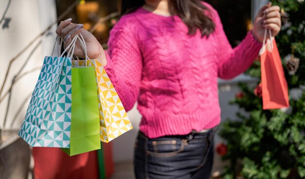 Gelukkig aziatisch meisje houdt boodschappentassen vast Xmas aanwezig vrolijke vrouw met Kerstmis Nieuwjaar Winterverkoop