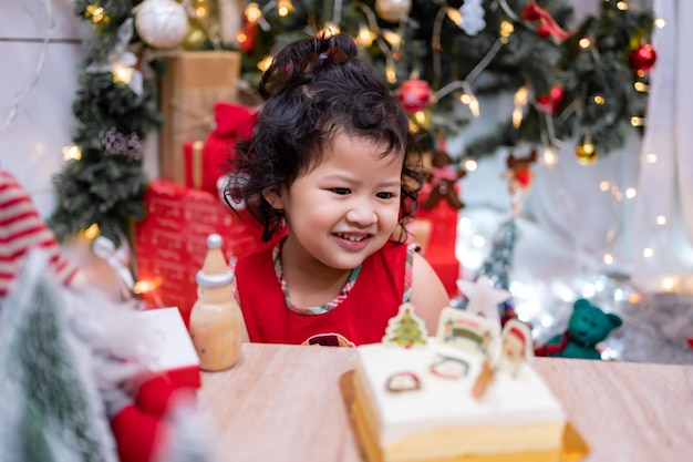 Gelukkig Aziatisch meisje met kerstcake thuis op wintervakantie met familie