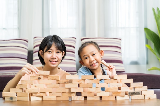 Gelukkig Aziatisch meisje met zus speelt thuis samen houten speelgoed