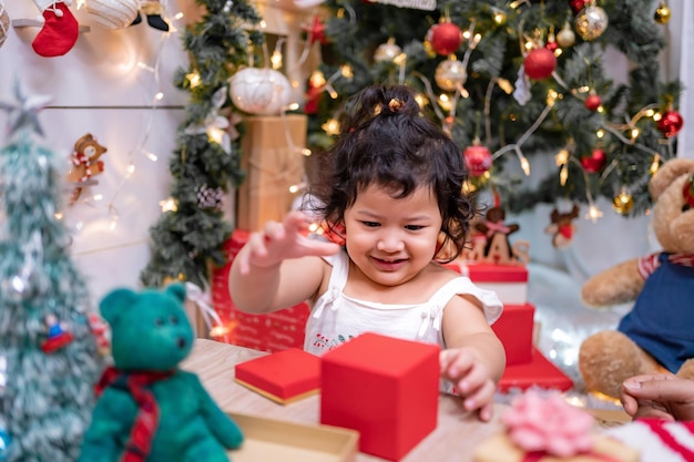 Gelukkig Aziatisch meisje veel plezier op eerste kerstdag. Kid met ouder met kerstboomversiering thuis op vakantie.