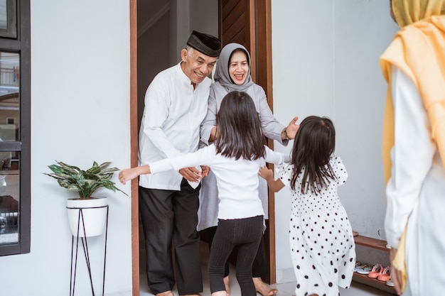 Gelukkig aziatisch moslim oud paar dat kinderen en kleinkinderen voor de deur ontmoet tijdens de viering van eid mubarak