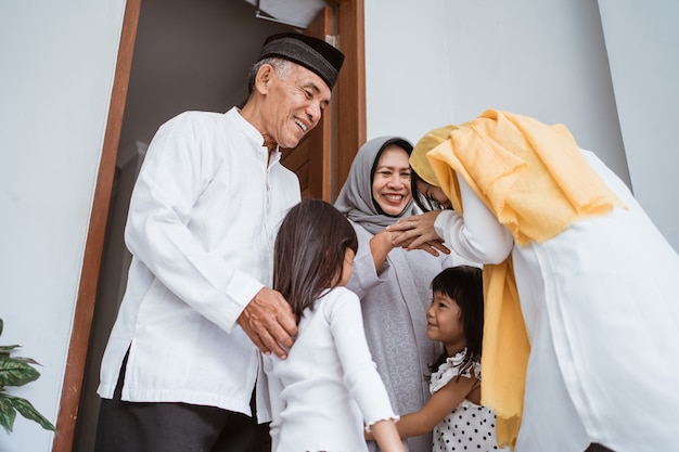 Gelukkig aziatisch moslim oud paar dat kinderen en kleinkinderen voor de deur ontmoet tijdens de viering van eid mubarak