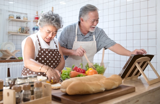 Gelukkig Aziatisch ouder hoger paar die verse maaltijd in keuken thuis koken.