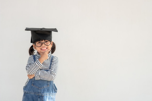 Gelukkig Aziatisch schoolkind afgestudeerd denken met afstudeerpet