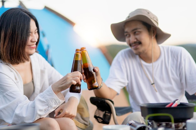 Gelukkig Aziatisch stel Gitaar spelen en zingen genieten van kamperen en bier drinken