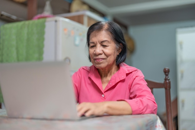 Gelukkig Aziatische bejaarde vrouw leren om een laptopcomputer thuis te gebruiken