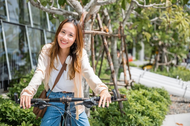 Gelukkig Aziatische jonge vrouw fietsten op straat buiten in de buurt van stad bouwen, Portret van lachende vrouwelijke levensstijl gebruik mountainbike in zomer reizen transportmiddelen, ECO vriendelijk, Urban fietsen