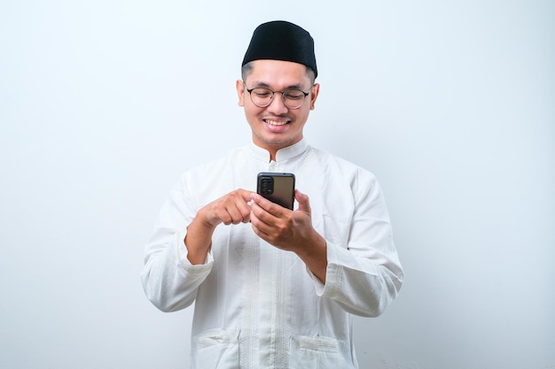 Gelukkig Aziatische moslim man houden en wijzen op mobiele telefoon op witte achtergrond Ramadan concept