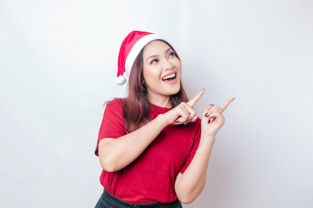 Gelukkig Aziatische Santa vrouw lacht en wijst naar haar kant geïsoleerd door witte achtergrond Kerst concept