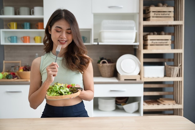 Gelukkig Azië vrouw salade eten in keuken kamer