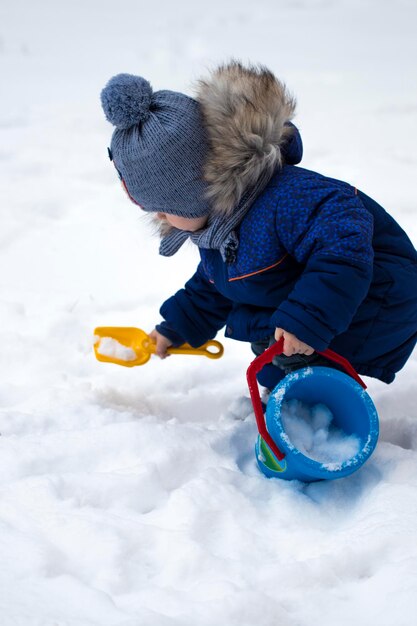 Gelukkig babyjongen spelen in de sneeuw.