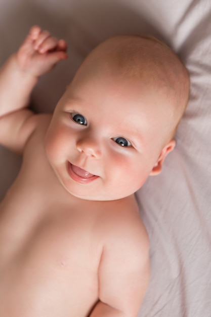 Gelukkig babymeisje dat op bed ligt