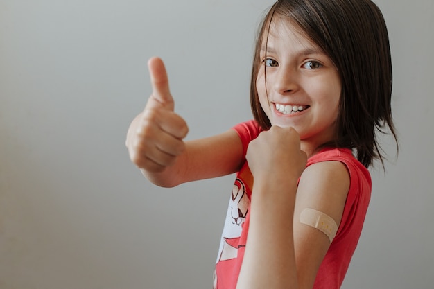 Foto gelukkig babymeisje na vaccinatie met een pleister op zijn schouder