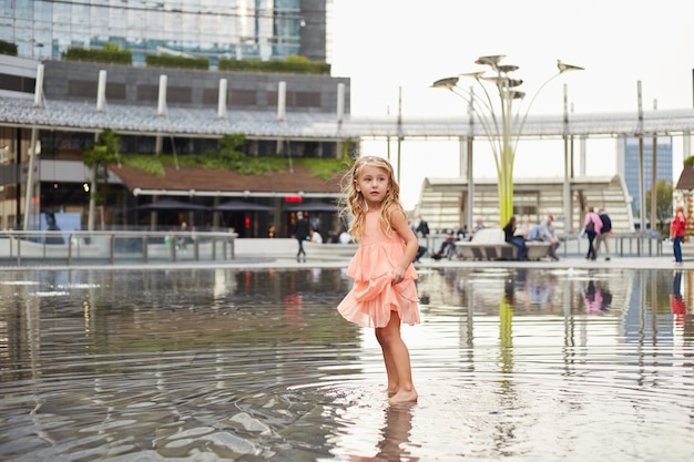 Gelukkig babymeisje speelt met water in een fontein op het plein