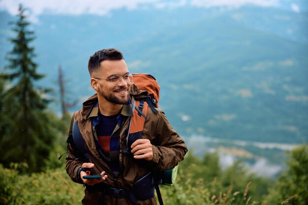 Gelukkig backpacker smartphone wandelen in de natuur op een regenachtige dag