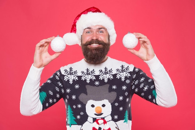 Gelukkig bebaarde man in warme gebreide trui en kerstman hoed houden boom decoratieve sneeuwballen vieren wintervakantie van chistmas, nieuwjaar decor.