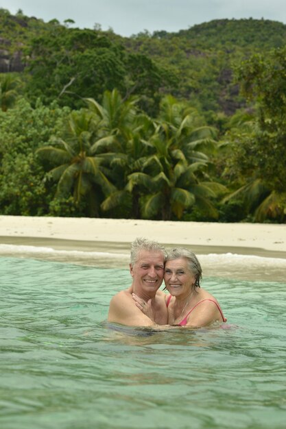 Gelukkig bejaarde echtpaar zwemmen op tropisch strand