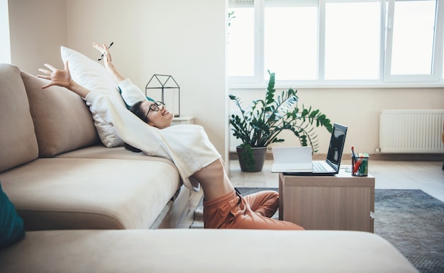 Gelukkig blanke vrouw die zich uitstrekt na het beëindigen van online lessen thuis op de vloer