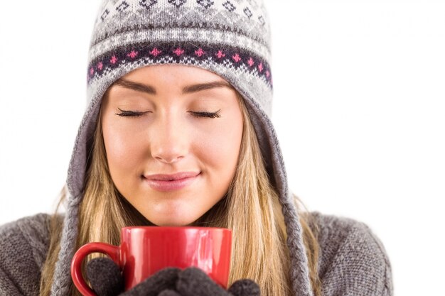 Gelukkig blonde in de winterkleren die mok houden