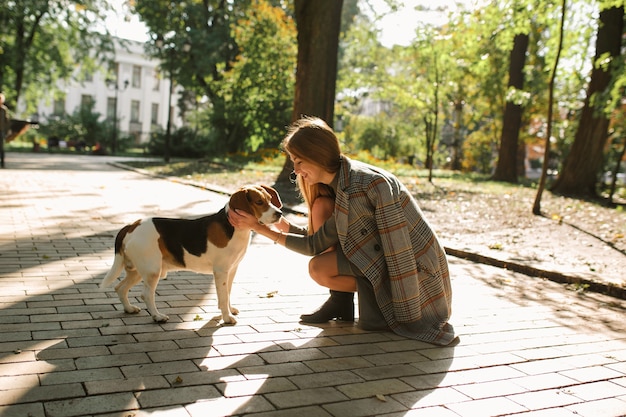 Gelukkig blonde vrouw met hond in het park in zonnige dag