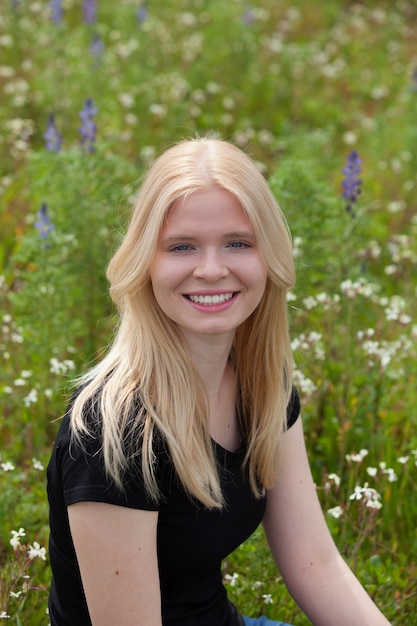 Gelukkig blondemeisje dat door bloemen wordt omringd