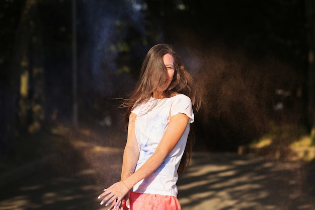 Gelukkig brunette aziatische vrouw spelen met droge verf op Holi kleuren festival