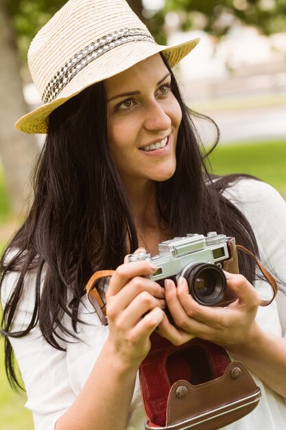 Gelukkig brunette in strohoed die retro camera houdt