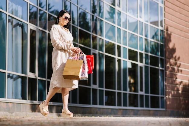 Gelukkig brunette vrouw met boodschappentassen buitenshuis. Shopoholic vrouw tevreden met de aankopen