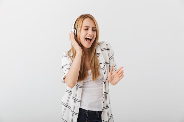 Gelukkig casual jongedame luisteren naar muziek met een koptelefoon