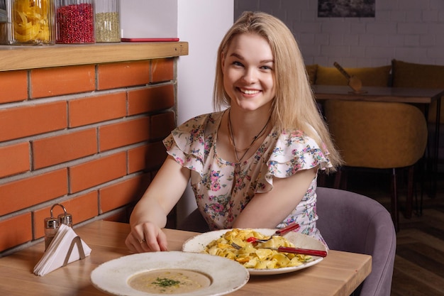 Gelukkig casual weared meisje zittend aan geserveerd voor een eettafel in restaurant