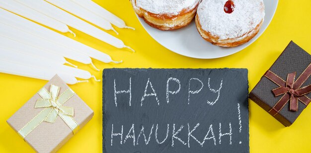 Gelukkig Chanoeka Joods dessert Sufganiyot op gele achtergrond Symbolen van religieuze jodendom vakantie Donuts kaarsen en cadeau