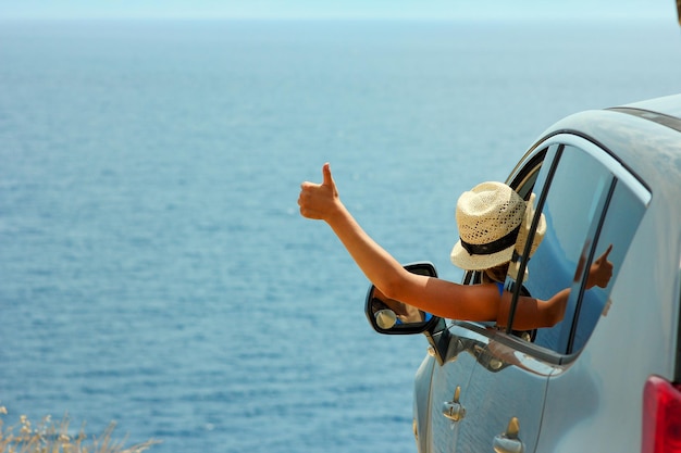 Gelukkig chauffeursmeisje in auto op zee in de zomer