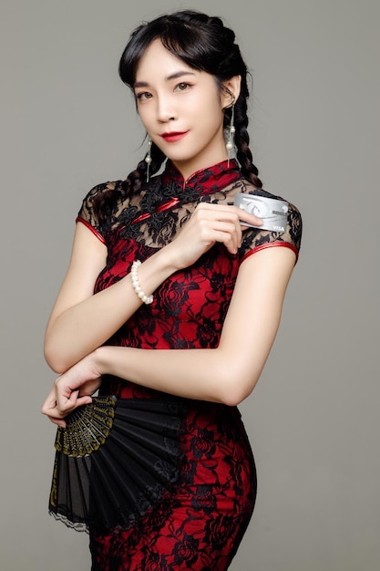 Gelukkig Chinees nieuwjaar Aziatische vrouw, gekleed in moderne cheongsam-jurk met een creditcard in de hand