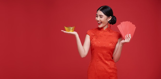 Gelukkig Chinees nieuwjaar Aziatische vrouw met angpao of rood pakket monetair geschenk en goudstaaf