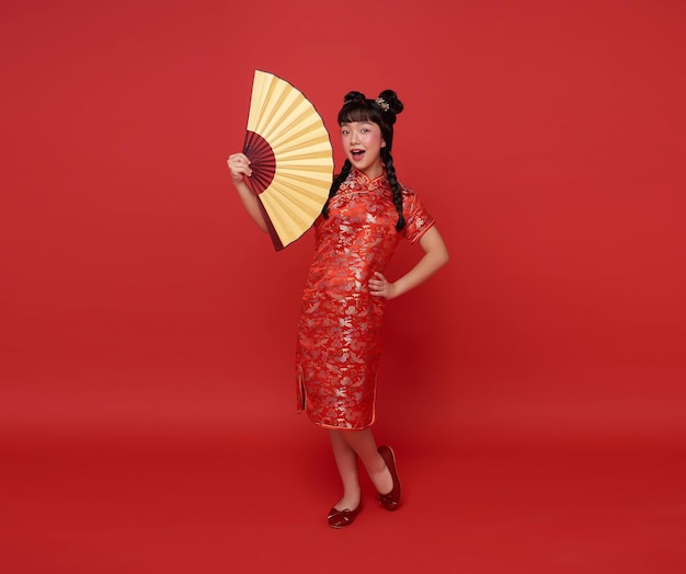 Gelukkig Chinees Nieuwjaar kinderen Aziatisch meisje draagt traditionele cheongsam qipao jurk met ventilator