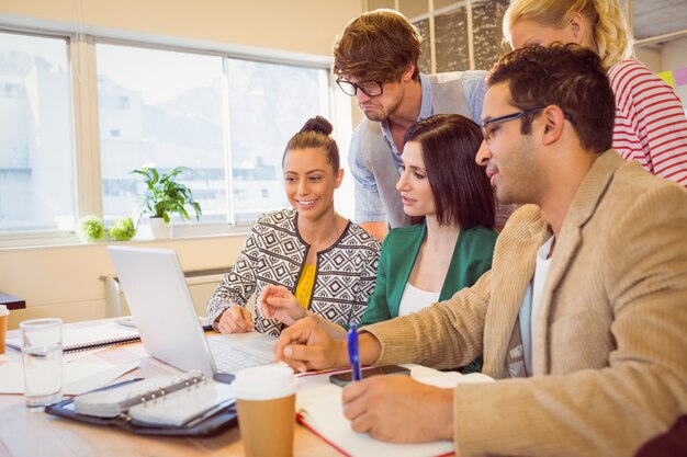 Gelukkig creatief commercieel team dat laptop in vergadering gebruikt