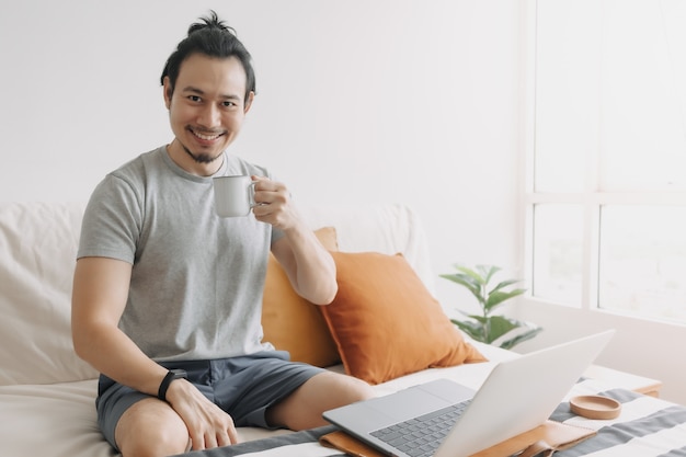 Gelukkig creatieve man werkt op laptop in zijn kantoor aan huis appartement