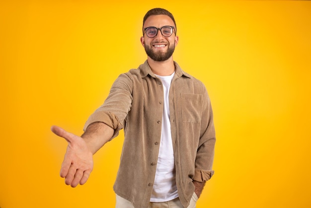 Gelukkig duizendjarige blanke man met baard in casual en glazen geven hand voor handdruk