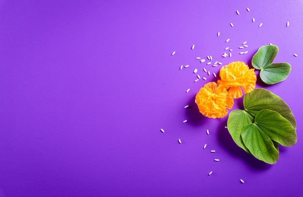 Gelukkig Dussehra. Gele bloemen, groen blad en rijst op paarse pastel achtergrond