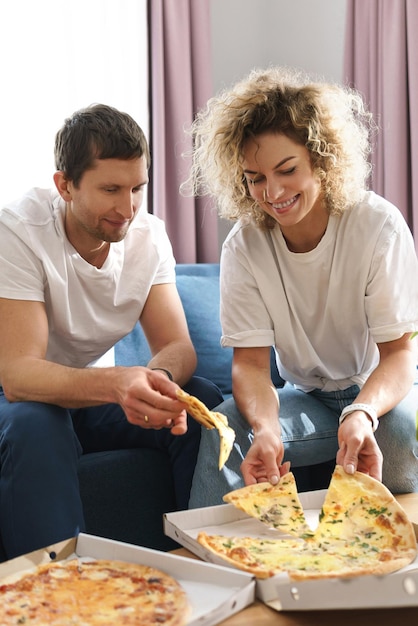 Gelukkig en hongerig paar dat heerlijke pizza thuis eet