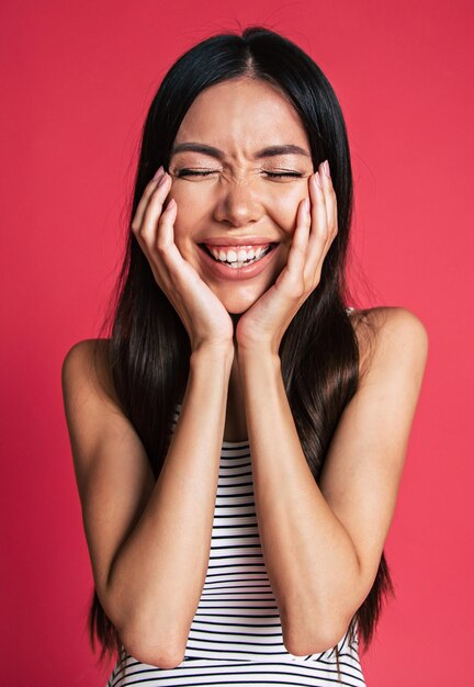 Gelukkig en opgewonden mooie jonge Aziatische vrouw portret geïsoleerd op roze achtergrond. Mensen emoties concept