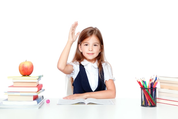 Gelukkig en schattig tienerschoolmeisje dat hand opsteekt in de klas