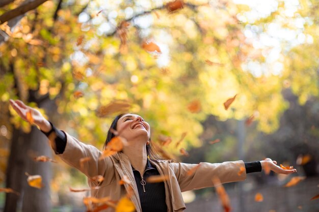 Gelukkig en stijlvol vrouwenportret in het herfstseizoen poseert ze met geel blad