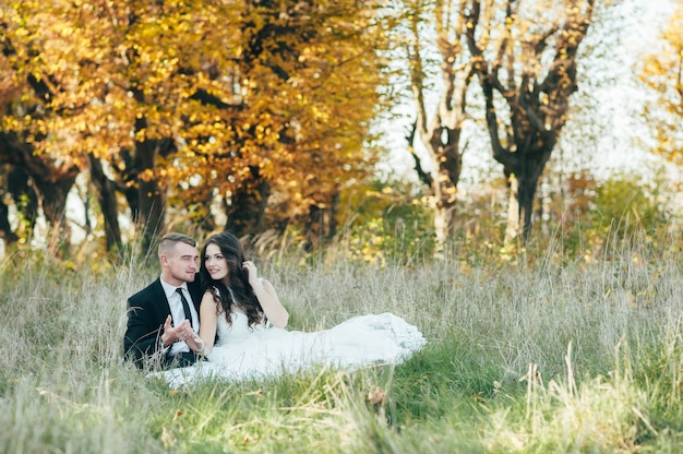 Gelukkig en verliefd bruid en bruidegom in herfst park op hun trouwdag