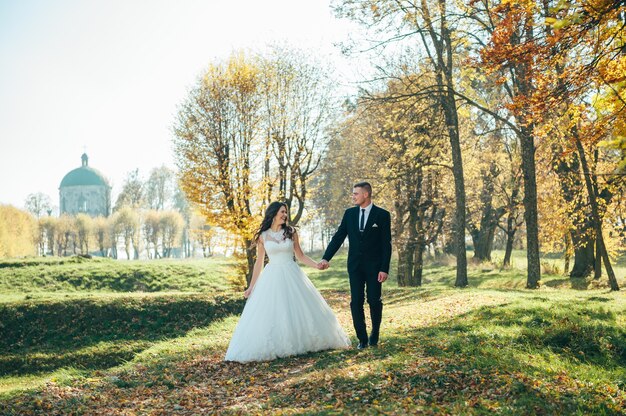 Gelukkig en verliefd bruid en bruidegom lopen in herfst park op hun trouwdag